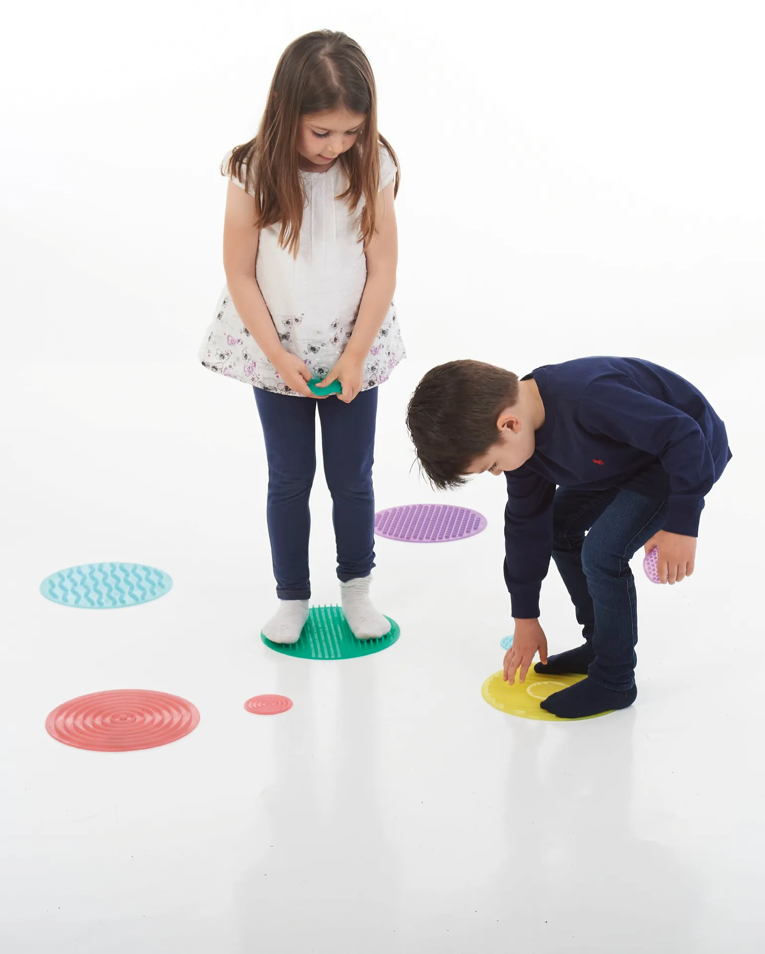 Zwei Kinder spielen mit dem Set Fühlmatten für Hand und Fuß, die eine unterschiedliche Oberfläche zu Erkunden besitzen
