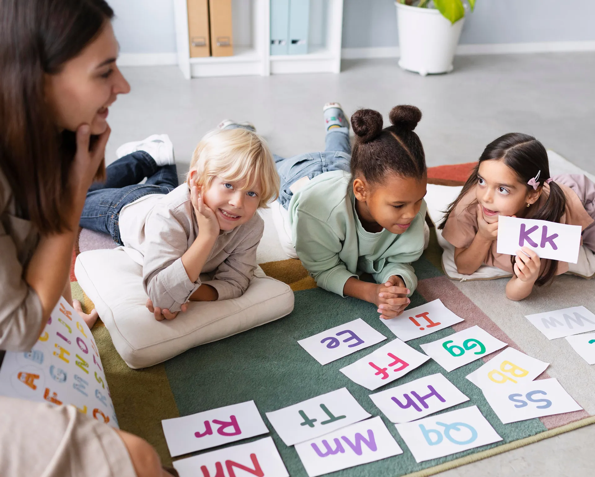 Kinder liegen auf dem Bodden und halten Buchstaben in die Luft