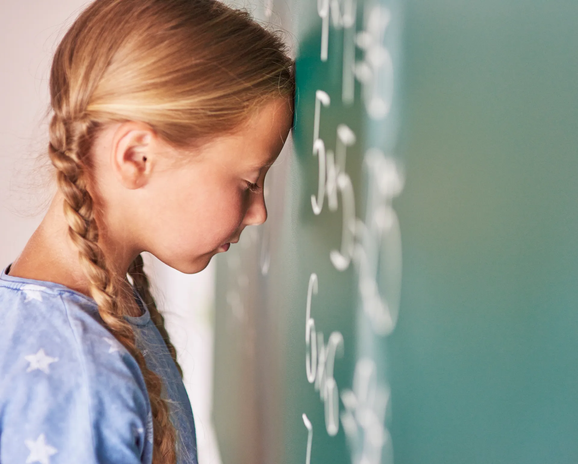 Mädchen, das ihren Kopf gegen die Tafel lehnt