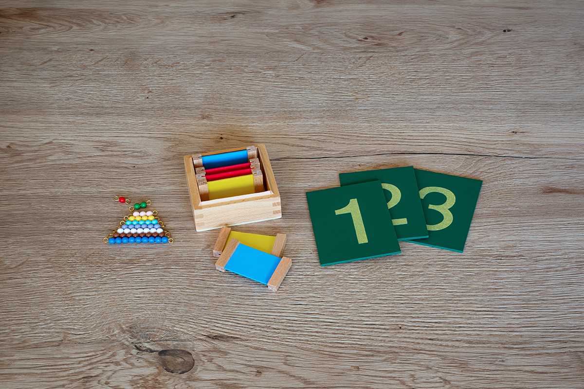 Auf einen Tisch liegen Farbtäfelchen, Sandpapier Ziffern und farbige Perlentreppe