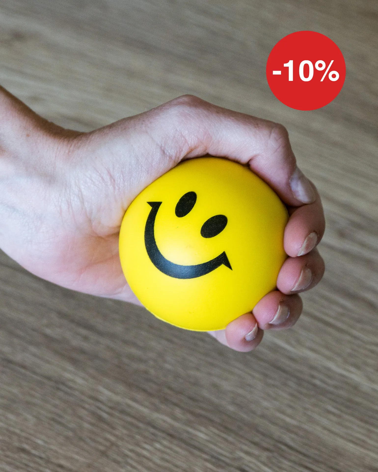 Hand hält einen gelben Softball mit lächelnden Gesicht 