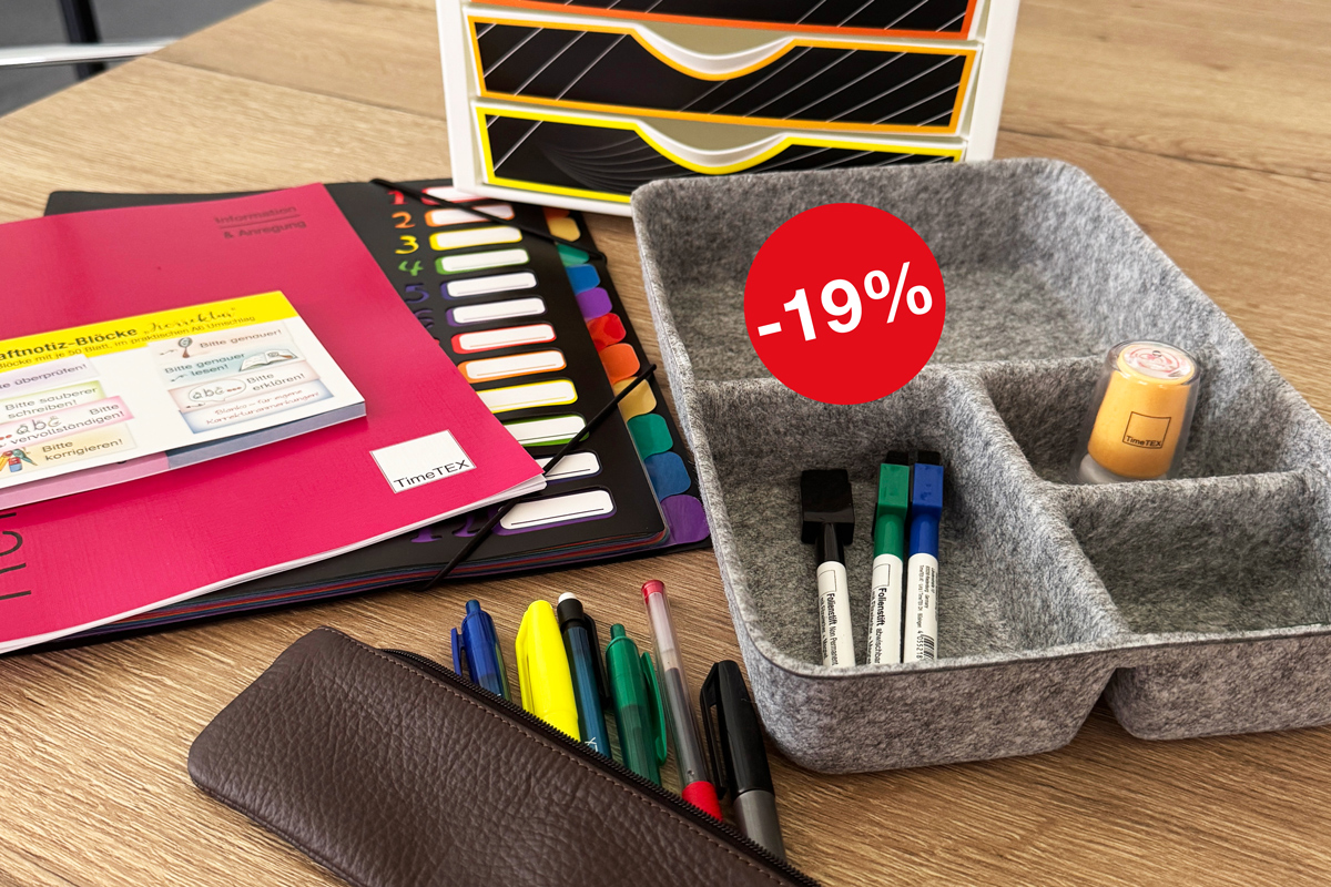 Auf einem Tisch liegen Planer, eine Fächermappe, Haftnotizen und eine graue Organisator-Box aus Filz mit Stiften und Stempeln