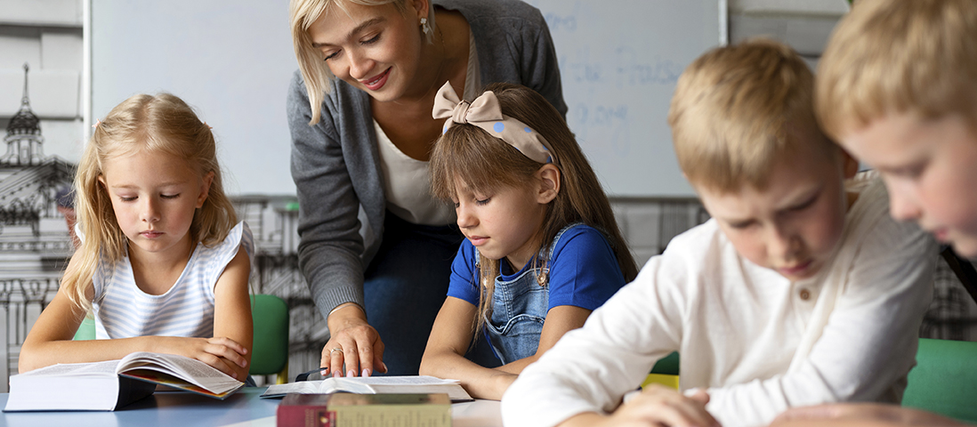 Kinder sitzen im Unterricht mit aufgeschlagenen Buch