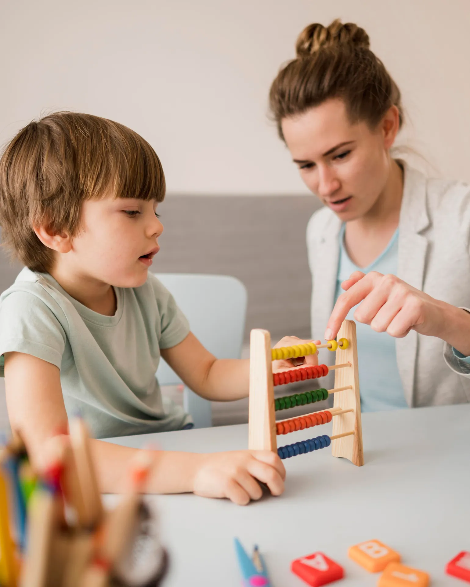 Junge, der von einer Lehrerin den Rechenrahmen erklärt bekommt