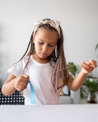 Kind bastelt mit einem Faden