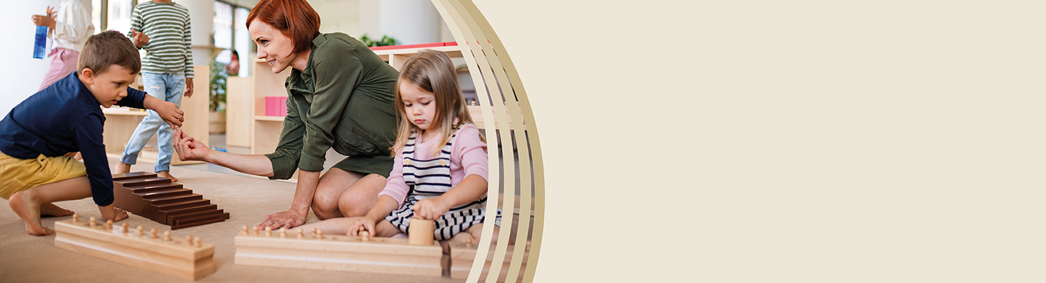 Frau sitzt mit zwei Kindern auf den Boden, die mit Montessori-Material spielen