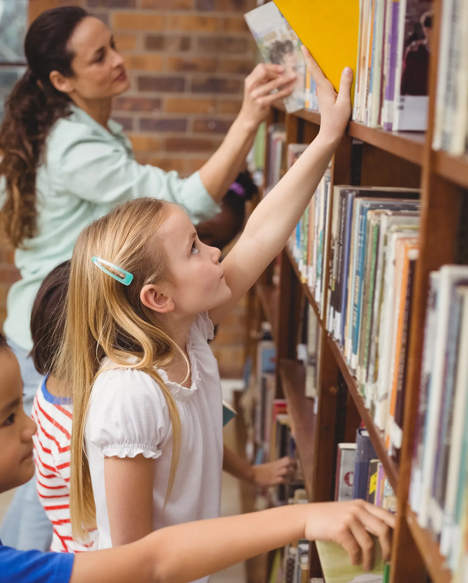 Kinder in einer Bücherei stellen Bücher zurück ins Regal
