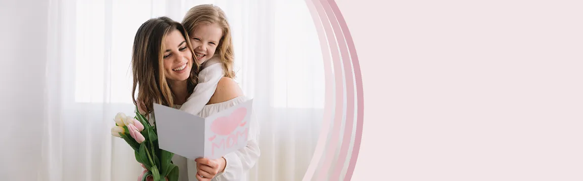 Glückliche Mutter mit Kind auf dem Arm und hat selbstgebastelte Karte zum Muttertag in der Hand sowie ein Strauß Tulpen 