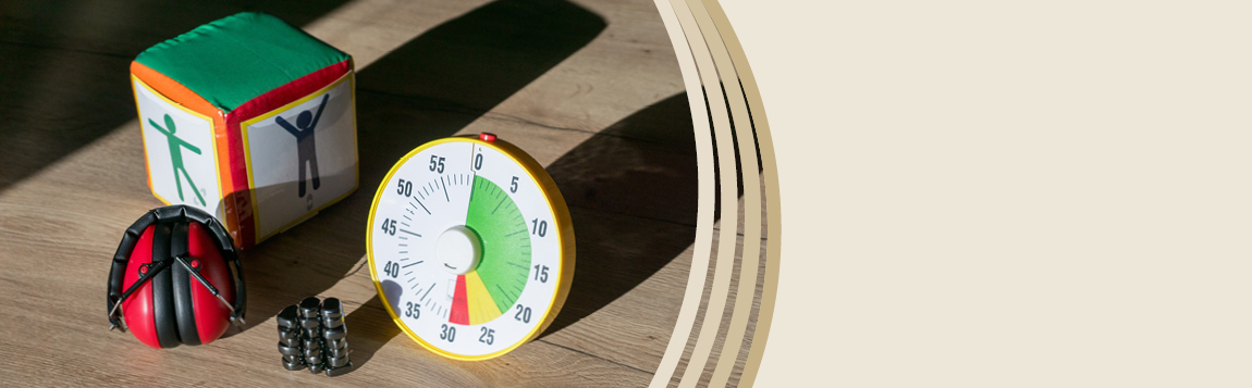 Auf einem Tisch liegen ein Gehörschutz rot, eine Zeitdauer-Uhr und Magnetische Steine