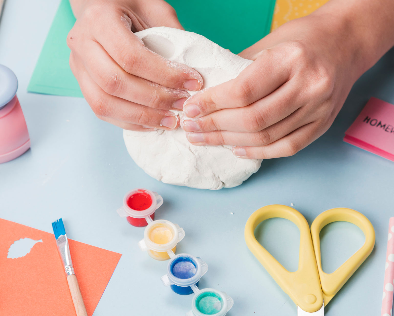 Materialien wie Tonpapier ein paar Acrylfarben mitsamt Pinseln liegen auf einen Tisch