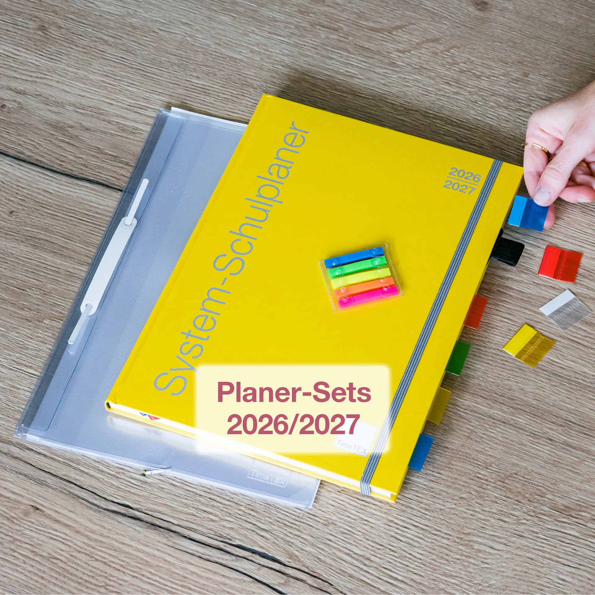 Auf einem Tisch liegt ein gelber System-Schulplaner mit bunten Register-Taben