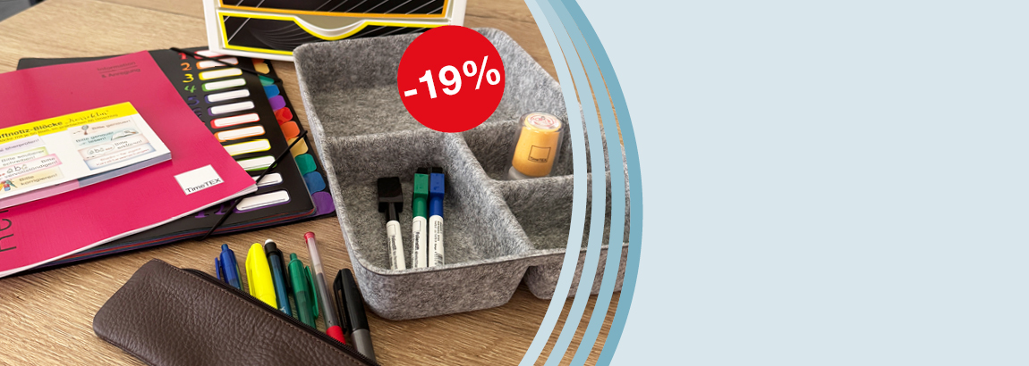 Auf einem Tisch liegen Planer, eine Fächermappe, Haftnotizen und eine graue Organisator-Box aus Filz mit Stiften und Stempeln