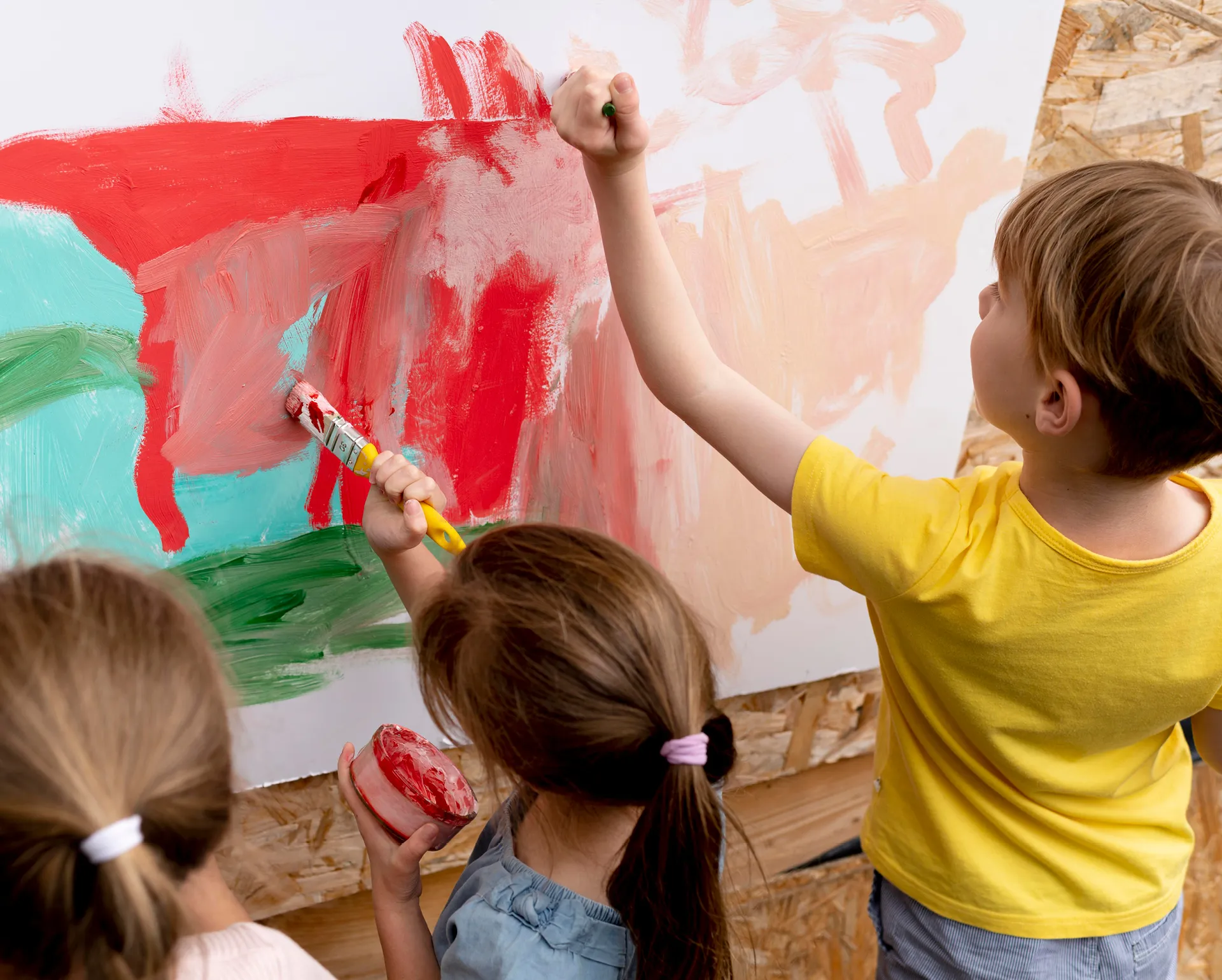 Mehrere Kinder bemalen eine Leinwand mit Pinseln