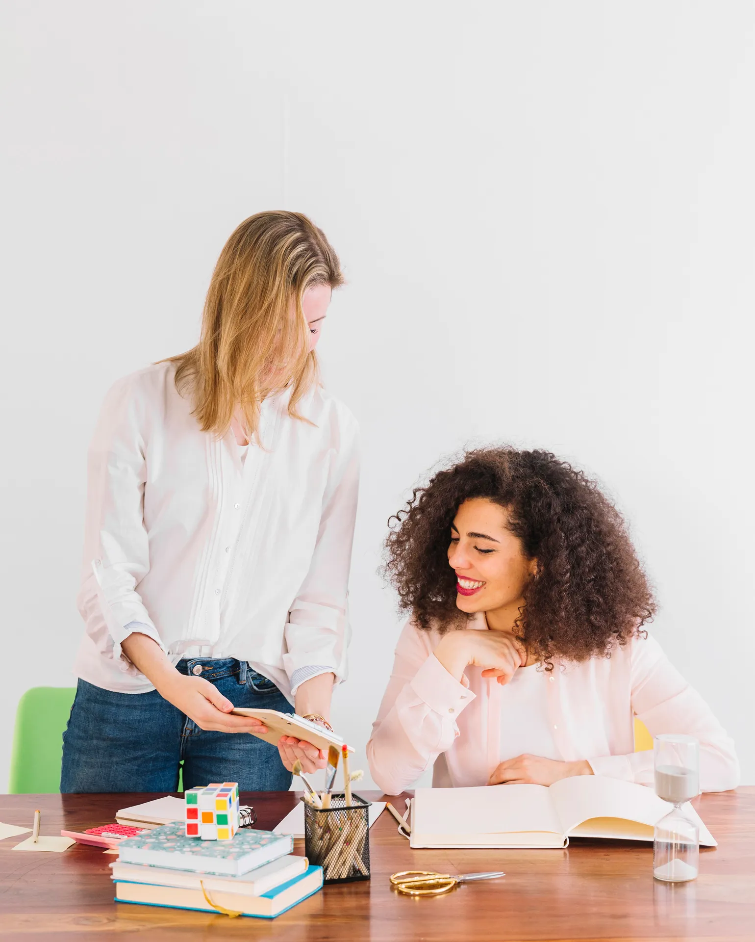 Zwei junge Frauen an einem Tisch, die Unterricht vorbereiten