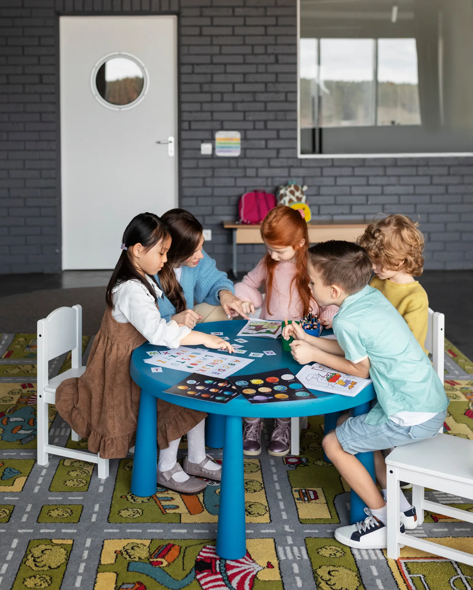 Fünf Kinder arbeiten an einem Tisch im Team an einer Aufgabe