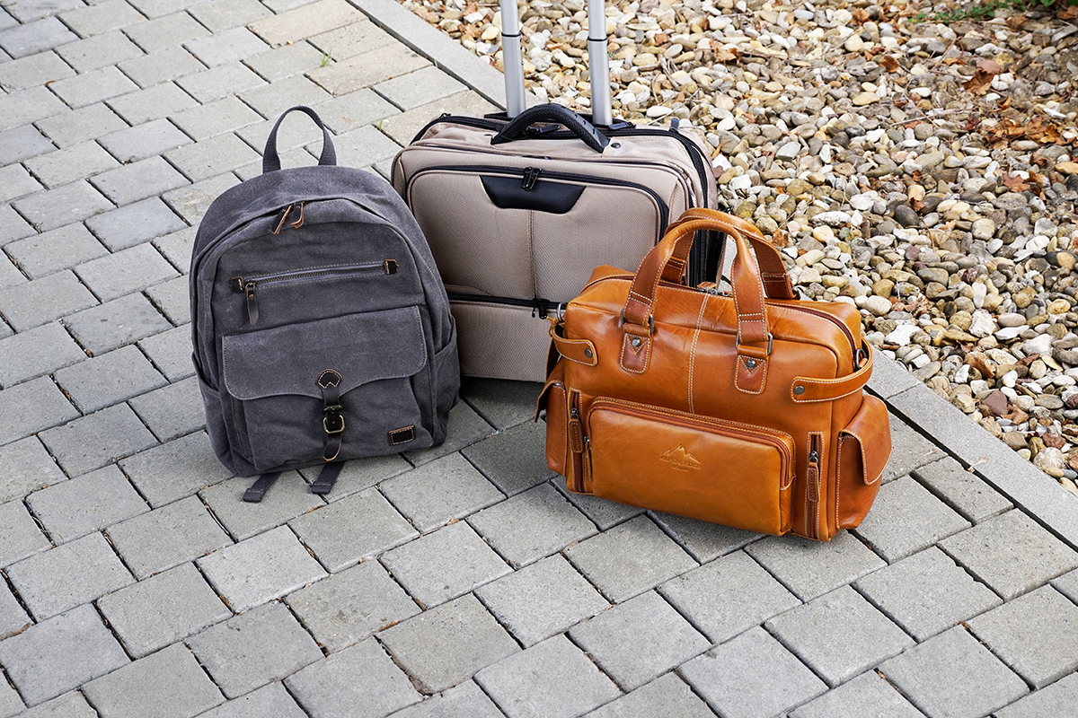Tasche aus Leder steht neben einen Trolley und einen Rucksack